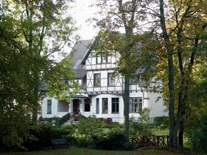 une maison blanche avec des arbres devant elle dans l'établissement Gutshaus Kubbelkow, à Bergen auf Rügen