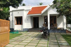 een motorfiets geparkeerd voor een wit huis bij Beautiful village house with all facilities. in Alleppey