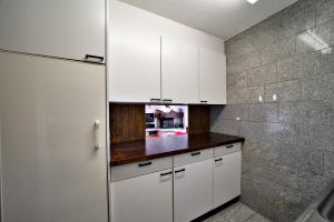 a kitchen with white cabinets and a tile wall at Chesa Aruons 21 - St. Moritz in St. Moritz