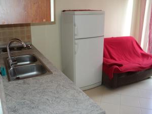 a kitchen with a refrigerator and a red blanket on a couch at Apartment Mandrač in Novigrad Istria