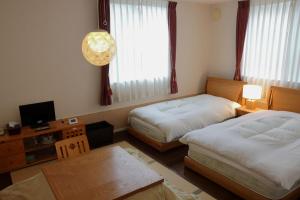 a hotel room with two beds and a television at RokuRoku in Kyoto