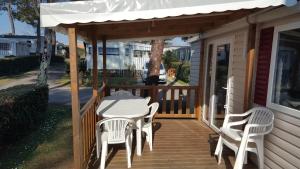 un portico con tavolo, sedie e tenda da sole di MH 149 4 pers camping Bois Dormant confort et détente a Saint-Jean-de-Monts