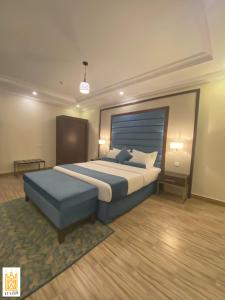 القصر للاجنحة الفندقية الضيافة1 في خميس مشيط: غرفة نوم مع سرير كبير والمسند الأزرق