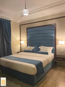 a bedroom with a large bed with a blue headboard at القصر للاجنحة الفندقية الضيافة1 in Khamis Mushayt