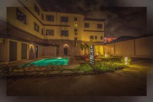 a swimming pool in front of a building at night at AKWA HIN Douala in Douala