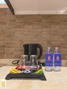 القصر للاجنحة الفندقية الضيافة1 في خميس مشيط: وعاء القهوة السوداء وزجاجتين من الماء على منضدة
