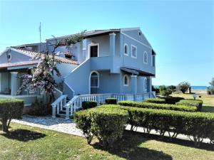 a blue house with bushes in front of it at Villa Angela, seafront apartments, Almiros beach in Almiros Beach