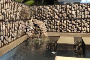 a retaining wall with a pool of water and rocks at Shakilla House 1A Syariah in Cianjur