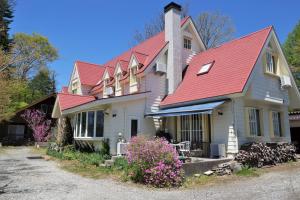 uma casa com um telhado vermelho em Cottage&Pension Love Thirty em Karuizawa