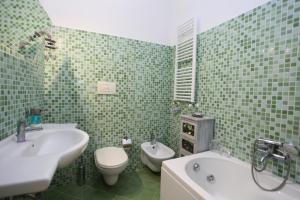 La salle de bains carrelée de couleur verte est pourvue d'un lavabo, de toilettes et d'une baignoire. dans l'établissement Casa Stella del Mattino, à Taormine