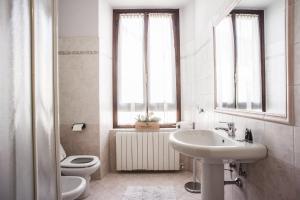 ein Bad mit einem Waschbecken, einem WC und Fenstern in der Unterkunft Case Vacanze ai Burattini in Adrara San Rocco + 12 Fotos