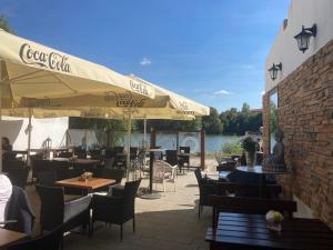 ein Restaurant mit Tischen und Sonnenschirmen und einem Körper aus Wasser in der Unterkunft Apartments near the pond in Prag