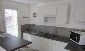a kitchen with white cabinets and a microwave at Appartement Pour 4 Personnes Dans Villa Dans Le Vent in Hossegor