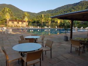 un patio con tavoli e sedie accanto a una piscina di Maresias Beach Home - Mata Azul a Maresias