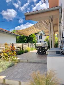 eine Terrasse mit einer Holzterrasse unter einem Sonnenschirm in der Unterkunft Villa La Plage Pour 7 Personnes A Proximite Du Port De Plaisance in Capbreton