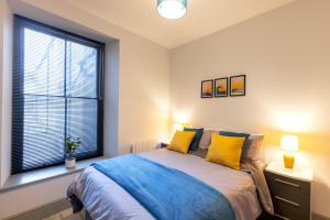 a bedroom with a bed with yellow pillows and a window at New central seafront apartment- stunning sea views in Aberystwyth