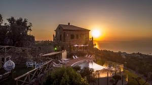 a building with a pool in front of a sunset at Agriresort Villa Edera in Massa Lubrense