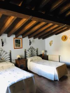 a bedroom with two beds and a ceiling with beams at La Escondida in Tornavacas