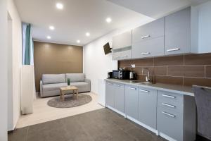 a kitchen with white cabinets and a couch in a room at Kőszeg Panzió in Kőszeg