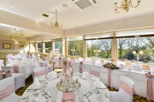 a banquet hall with white tables and chairs and windows at Mercure Manchester Norton Grange Hotel & Spa in Rochdale