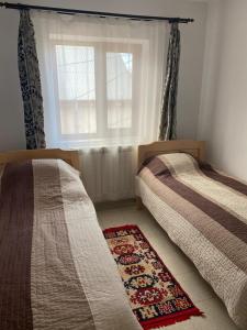 2 camas en un dormitorio con ventana y alfombra en Casa Mărguța, en Iaşi