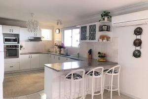 a kitchen with white cabinets and a island with bar stools at Mountain Living with Ocean views in Mount Tamborine