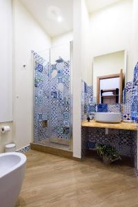 ein Bad mit blauen und weißen Fliesen und einer Dusche in der Unterkunft Incao Holiday I Pupi House in Cefalú