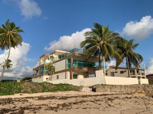 a building on the beach with two palm trees at Casa de Praia Pitimbu in Pitimbu