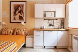 a small kitchen with white cabinets and a bed at Призрак оперы in Saint Petersburg