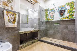 a bathroom with a sink and a shower with paintings on the wall at Incao Holiday Il Moro House in Cefalù