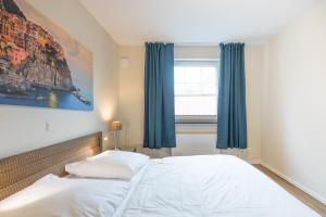 Schlafzimmer mit einem Bett mit blauen Vorhängen und einem Fenster in der Unterkunft Austernfischer in Husum in Husum