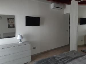 een witte slaapkamer met een bed en een tv aan de muur bij B&B La Genuina in Guspini