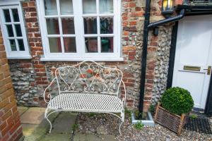 a white bench in front of a brick building at 1 bedroomed Cottage near quay in Blakeney