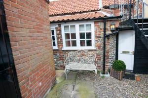 a white bench sitting in front of a brick building at 1 bedroomed Cottage near quay in Blakeney