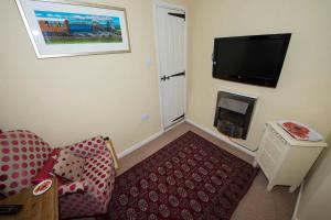 a living room with a couch and a flat screen tv at 1 bedroomed Cottage near quay in Blakeney