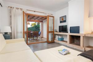 sala de estar con sofá blanco y TV en APARTAMENTO JARDIN REY COLAU con piscinas y vistas al mar, 100m de la playa Cala Marsal, en Portocolom