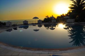 a swimming pool with the sunset in the background at Holiday Apartments Maria with Pool and Panorama View - Agios Gordios Beach in Agios Gordios