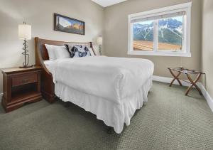 ein Schlafzimmer mit einem großen Bett und einem Fenster in der Unterkunft Sunset Ridge - Luxurious Corner Condo - Spectacular Mt Views with open Pool! in Canmore