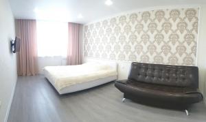 ヤロスラヴリにあるApartment on 8 Marta 17Aのベッドルーム1室(ベッド1台、黒い革張りの椅子付)