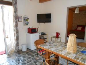 ein Esszimmer mit einem Tisch mit Stühlen und einem Fernseher in der Unterkunft La Dame Blanche in Saint-Maurice-dʼIbie