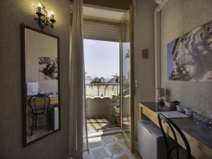 a bathroom with a mirror and a table with chairs at L'Onda in Marina di Ragusa