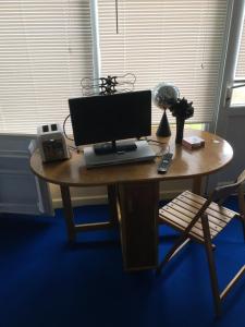 a computer monitor sitting on a wooden table with a chair at Adventure Cabin in Dartmouth