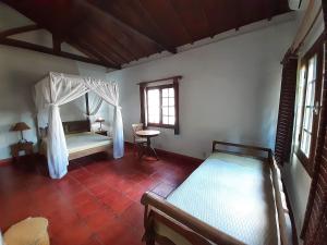 a bedroom with two beds and a table and a window at Pousada Fazenda Xaraés in Todos os Santos