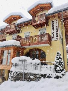 una casa cubierta de nieve delante de ella en Hotel Mountain Resort en Commezzadura