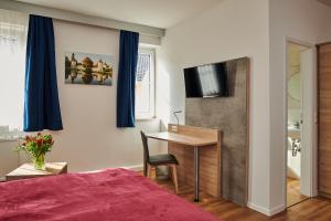 a bedroom with a bed and a desk and a television at Zur Allacher Mühle in Munich