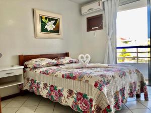 1 dormitorio con 1 cama con colcha de flores y ventana en Kasato Maru Residence, en Florianópolis