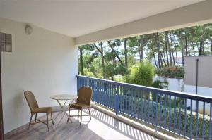 a balcony with two chairs and a table and a large window at Appartement Pour 2 Personnes Vue Sur Le Port- Residence Jean Rameau in Hossegor
