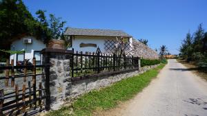 a fence next to a road next to a house at Xóm CAT GardenHouse Phú Yên in Tuy Hoa