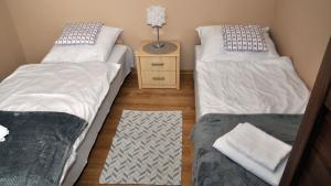 a room with two twin beds and a night stand at Apartamenty Ster Darłówko in Darlowko