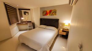 a bedroom with a bed and a table and a window at Hotel Boutique Calle Grande in Valledupar